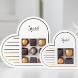 Elegant hvid hjerteformet æske med gyldne detaljer, fyldt med 9 håndlavede chokolader i smagsvarianterne nougat, marcipan, flødekaramel og saltkaramel – en perfekt lille gave til en, du holder af.