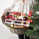 Stor luksuskurv fyldt med chokolade, lakrids og håndplukkede delikatesser, smukt præsenteret i en fletkurv indpakket i cellofan og pyntet med gavebånd