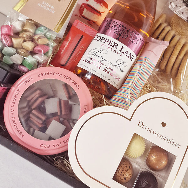 Smuk gavekurv med rosévin og lyserøde lækkerier